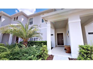 Inviting front entrance with well-maintained landscaping, brown door, and decorative wall art at 3083 Tom Sawyer Dr, Kissimmee, FL 34746