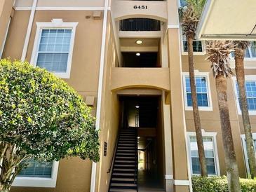 Attractive condo building with stairwell, large windows, and nearby mature trees and landscaping at 6451 Old Park Ln # 102, Orlando, FL 32835
