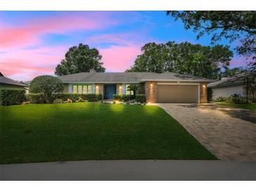 Charming single-story home with lush landscaping, brick accents, and a paver driveway at 7549 Lake Marsha Dr, Orlando, FL 32819