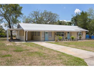 Inviting single-story home featuring a metal roof, covered front porch, and charming blue doors at 88 E Charlotte Ave, Eustis, FL 32726