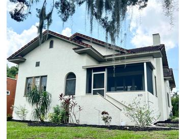 Charming stucco home featuring a tile roof, landscaped yard, and a cozy screened porch, blending classic charm with modern comfort at 900 Carlton Ave, Lake Wales, FL 33853