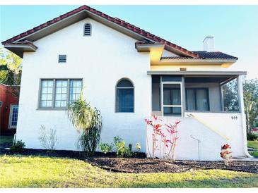 Charming home with a stucco exterior, terra cotta roof, a screened porch, and landscaped front yard at 900 Carlton Ave, Lake Wales, FL 33853