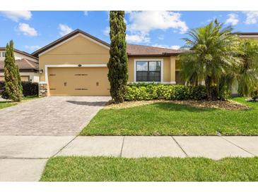 Inviting single-story home with a well-manicured lawn and paver driveway, showcasing curb appeal at 10111 Tierra Bella Dr, Orlando, FL 32825
