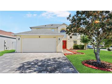 Two-story home with a two car garage, brick driveway, and bright red front door at 11257 Dacre Ln, Orlando, FL 32824