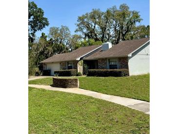 Charming one-story home featuring brick accents, lush landscaping, and mature trees, creating a welcoming curb appeal at 1219 Serissa Ct, Orlando, FL 32818