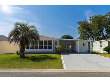 Inviting home with a well manicured lawn, carport, and a charming palm tree at 1220 Zapata Pl, Lady Lake, FL 32159