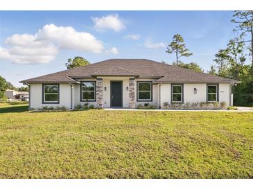 Charming single-story home featuring a manicured lawn, neutral stucco, stone accents, and a welcoming dark front door at 19073 Sabal St, Orlando, FL 32833