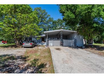 Charming single-story home featuring a covered parking area and mature trees on a sunny day at 2304 N Hastings St, Orlando, FL 32808