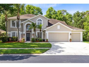 A well-manicured two-story home featuring a three-car garage, arched entryway, and lush landscaping at 2607 Stanmore Ct, Orlando, FL 32817