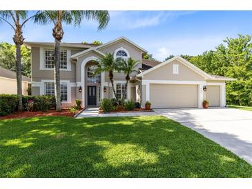 Inviting two-story home with a three-car garage, lush lawn, and elegant landscaping at 2607 Stanmore Ct, Orlando, FL 32817
