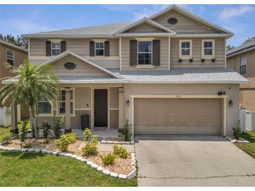 Charming two-story home with a well-manicured lawn, complemented by a two-car garage and neutral color scheme at 325 Aldridge Ln, Davenport, FL 33897