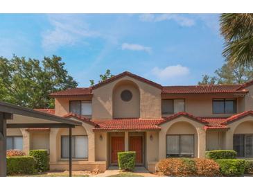 Two-story townhome with stucco facade, red tile roof, and landscaped front with covered parking at 424 Club Dr, Winter Springs, FL 32708