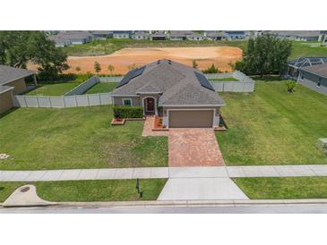 Charming single-story home with a well-manicured lawn, brick driveway, and neutral tones offers great curb appeal at 5515 Windsong Oak Dr, Leesburg, FL 34748