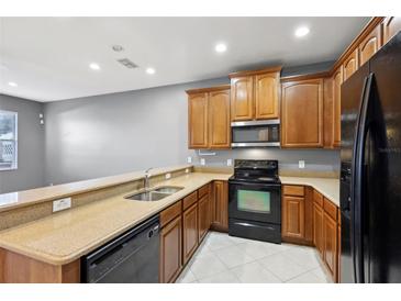 Well-lit kitchen features wood cabinets, granite counters, black appliances, and double bowl sink at 585 Cruz Bay Cir, Winter Springs, FL 32708
