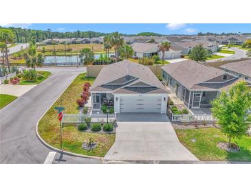 Charming single-story home boasts a manicured lawn, picket fence, and view of the pond in a peaceful community at 6223 Atkinson Ln, The Villages, FL 32163