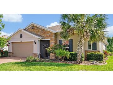 Charming single-story home featuring a stone facade, well-manicured lawn, and a mature palm tree at 634 Via Corso Ct, Kissimmee, FL 34759