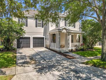Charming two-story home featuring a welcoming front porch, dark shutters, and a spacious driveway and two-car garage at 9942 Sweetleaf St, Orlando, FL 32827