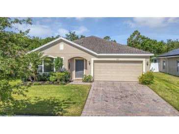 Charming single-story home with lush landscaping and a brick-paved driveway at 2426 Addison Creek Dr, Kissimmee, FL 34758