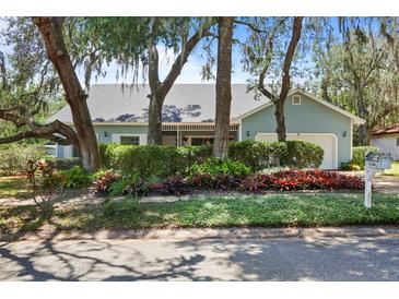 Charming single-story home featuring light-blue siding, mature trees, and lush landscaping at 8554 Amber Oak Dr, Orlando, FL 32817