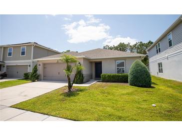 Well-maintained single-story home with a manicured lawn, decorative shrubbery, and attached two-car garage at 13851 Rushing Creek Run, Orlando, FL 32824