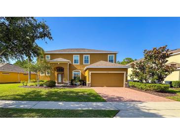 Charming two-story home with a well-manicured lawn and inviting brick driveway at 206 Yellow Snapdragon Dr, Davenport, FL 33837