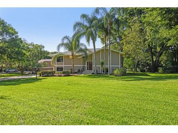 Charming two-story home with a sprawling green lawn and mature landscaping, including palm trees at 33925 Highland Rd, Leesburg, FL 34788