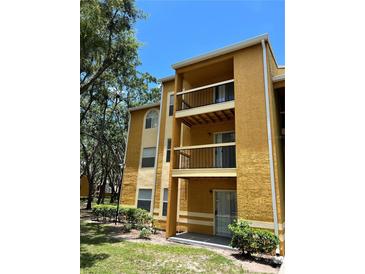 A three-story condo building with balconies, mature trees and nice landscaping at 5291 Images Cir # 301, Kissimmee, FL 34746