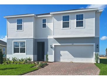 Two-story home with a two-car garage, red brick driveway, and manicured landscaping at 7779 Trapani Loop, Clermont, FL 34714
