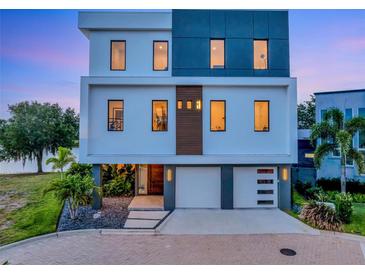 Modern three-story home with a two-car garage, manicured landscaping, and stylish design at 8157 Elion St, Orlando, FL 32827