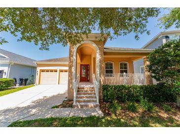 Inviting tan home with a striking arched entrance, two-car garage, and a cozy porch with white railing at 10076 Kimble Field Way, Orlando, FL 32827