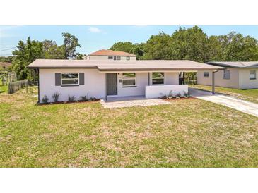 Exterior shot of home with front lawn, covered porch, updated facade, landscaping, and driveway at 1118 Roberta Ave, Orlando, FL 32825