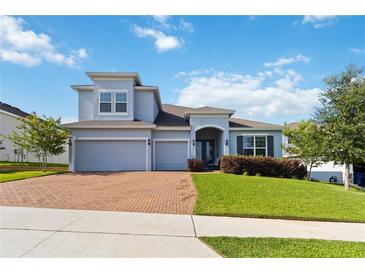 Well-maintained two-story house with a three-car garage, brick paved driveway, and lush green lawn at 1265 Blarney St, Minneola, FL 34715
