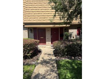 Charming townhome exterior with brick facade, red doors, and lush landscaping at 200 Saint Andrews Blvd # 3002, Winter Park, FL 32792