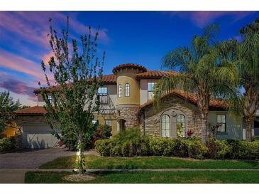 Stately home features a stone turret, tile roof, manicured landscaping, and a side entry two-car garage at 3844 Bowfin Trl, Kissimmee, FL 34746