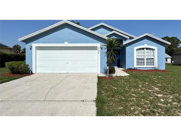 Charming single-story home with a well-maintained lawn, and a white garage door at 703 Tartan Loop, Lake Wales, FL 33853