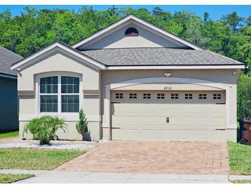 Charming home features a two-car garage, brick driveway, manicured landscaping, and a well-maintained lawn at 2456 Varenna Loop, Kissimmee, FL 34741