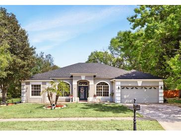 Charming single-story home with a manicured lawn, arched windows, and a two-car garage at 3451 Players Point Loop, Apopka, FL 32712