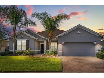 Charming single-story home with a two-car garage, beautiful landscaping, and tropical palm trees against a colorful sunset backdrop at 3925 Green Sabal Dr, Orlando, FL 32824