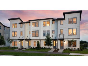 Modern townhome with a charming exterior, beautiful landscaping, and a well-lit entryway creating a welcoming ambiance at 8460 Sperry St, Orlando, FL 32827