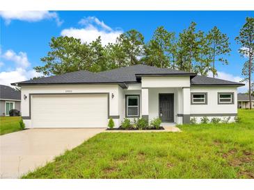 Charming single-story home featuring a two-car garage, modern design, and well-manicured lawn at 13525 Se 100Th Ave, Belleview, FL 34420