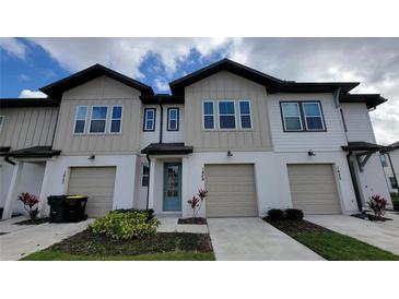 New construction townhome features neutral siding, an attached garage, and manicured landscaping at 1429 Discovery St, Davenport, FL 33896