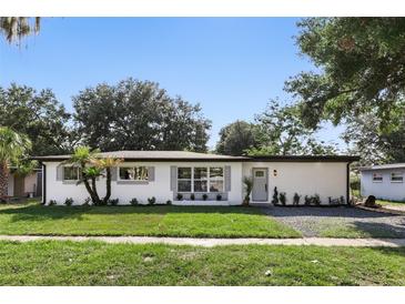 Charming single-story home with white exterior, gray shutters, complemented by a green lawn and mature landscaping at 606 Faber Dr, Orlando, FL 32822