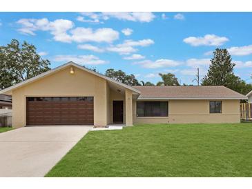 Charming single-story home featuring a well-manicured lawn, brick accents, and a two-car garage with a brown door at 622 N Goodrich Dr, Deltona, FL 32725