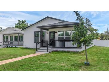 Charming home with a covered front porch, brick walkway, manicured lawn, and fresh white paint at 1050 20 St, Orlando, FL 32805