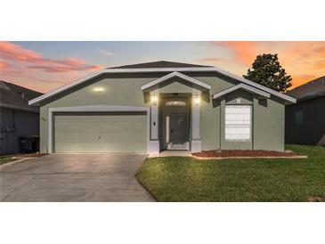 Charming single-story home with a well-manicured lawn and a two-car garage at sunset at 1111 High Vista Dr, Davenport, FL 33837