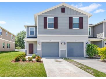 Charming two-story home with gray siding, two-car garage, and meticulously landscaped front yard at 1396 Mirabella Cir, Davenport, FL 33897