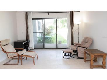 Bright living room featuring neutral tile flooring and large sliding glass doors to the outside at 1504 Virginia Ave # 105, Daytona Beach, FL 32114