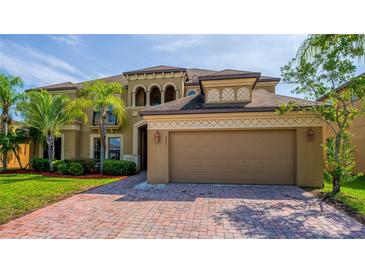 Elegant two-story home with a two car garage, lush landscaping, and a paver driveway at 3041 Boating Blvd, Kissimmee, FL 34746