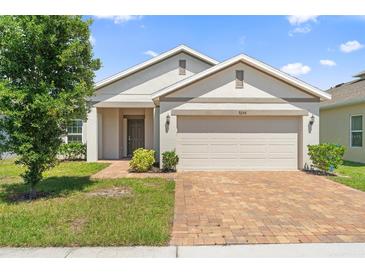 Charming single-story home featuring a brick driveway, a two-car garage, and a neatly maintained lawn at 9356 St Therese St, Groveland, FL 34736