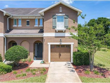 Charming two-story townhome featuring a one car garage and professionally landscaped front yard at 1551 Peterson Pl, Sanford, FL 32773